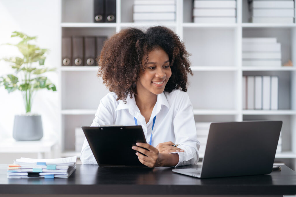 Businesswomen hand working with tablet and laptop computer with documents on office desk in modern office.